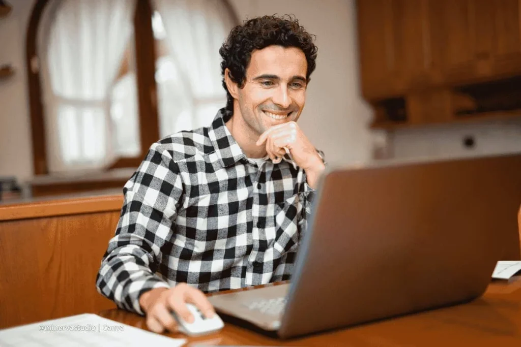 Hombre sonriente trabajando en laptop desde casa