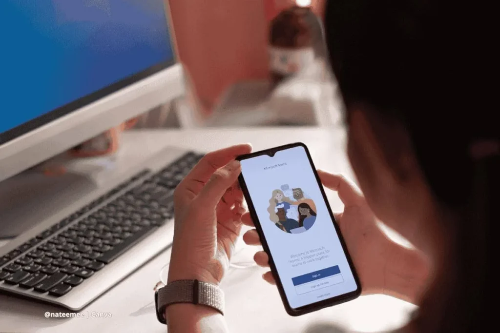 Mujer accediendo a Microsoft Teams desde un celular frente a computadora