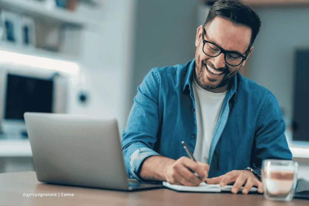 Hombre trabajando desde casa con portátil y cuaderno