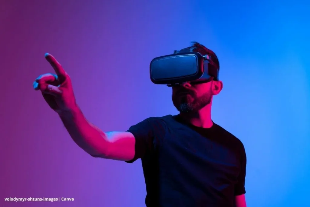 Metaverso en Colombia 2025: la próxima frontera para negocios e interacción social 2 Hombre con gafas de realidad virtual señalando en espacio digital iluminado en tonos azul y rosa.